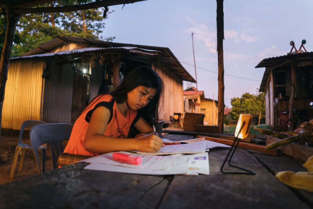 A girl in La Union, Philippines studies outdoors at dusk with a solar study light