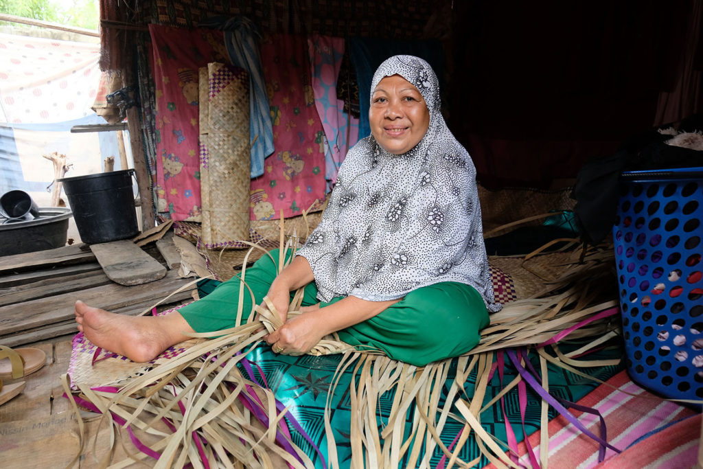 A Filipino mat weaver works with plant strips in an evacuation camp in Maguindanao