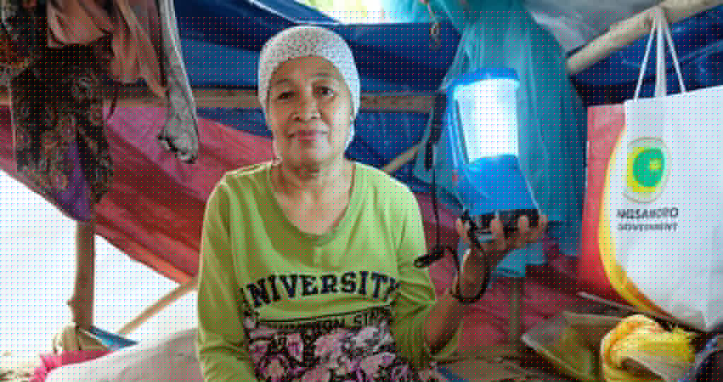 Zulaika Lamikan holds the portable solar lamp that lets her weave after dark